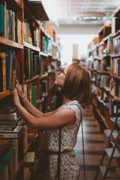 woman searching library bookshelves